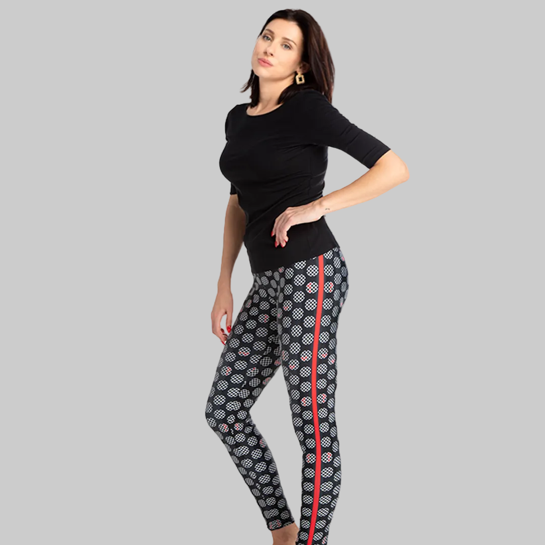 Woman wearing a black top and patterned leggings with a red stripe on a white background