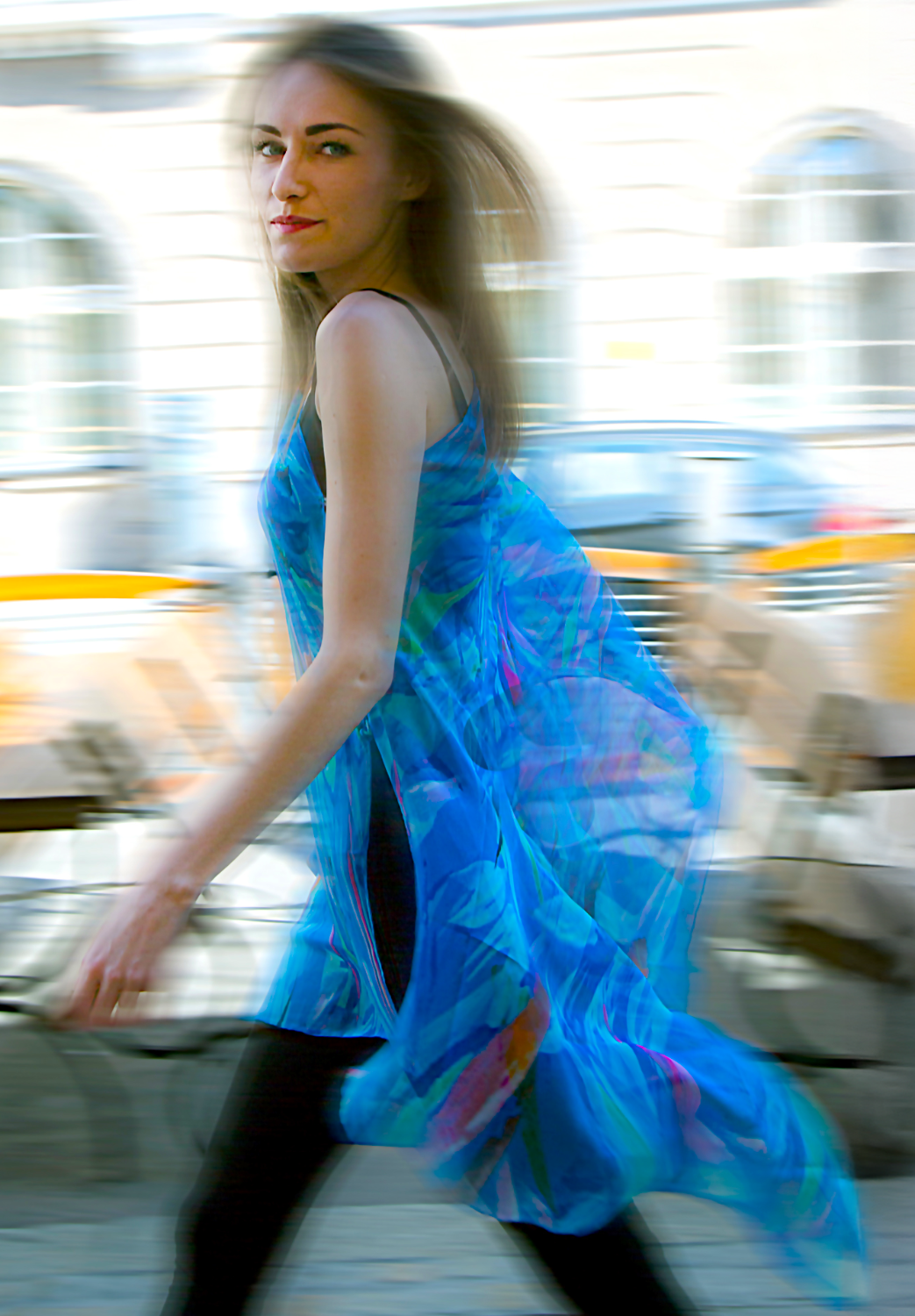 Woman wearing a blue LuLuWrap dress with colorful patterns, blurred background