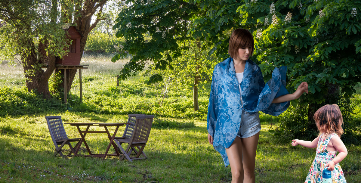 Woman and child in a garden setting, wearing a blue print silk LuLuWrap.