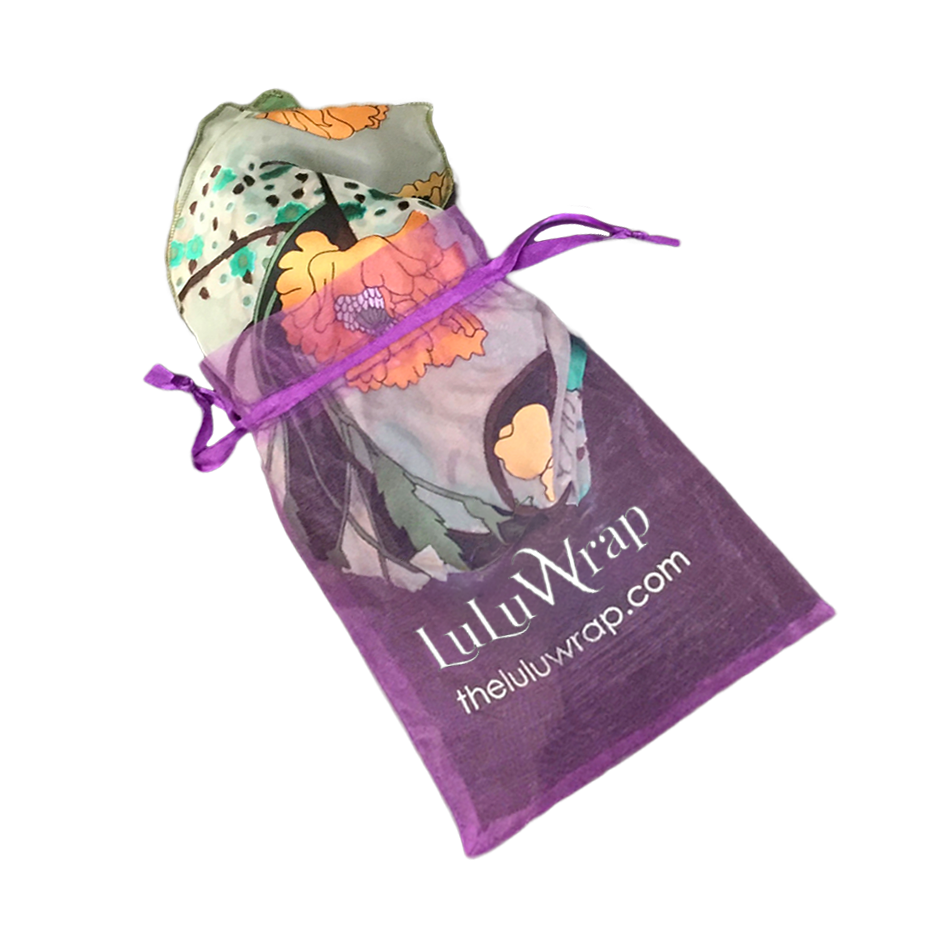 A purple drawstring pouch with the brand name 'LuluWrap' and website printed on it, containing a rolled multicolor floral fabric wrap or scarf, isolated on a white background.