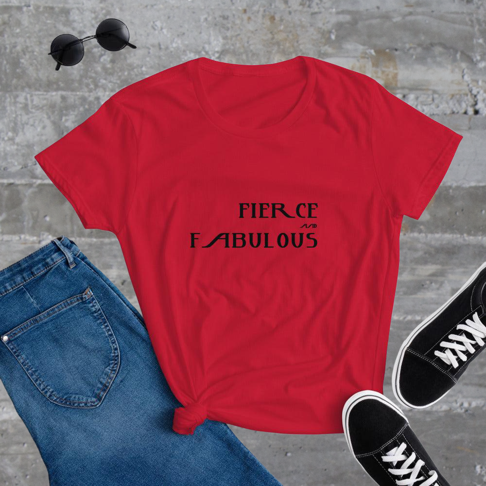 Red t-shirt with 'FIERCE & FABULOUS' text, blue jeans, and black sneakers on a gray concrete surface.